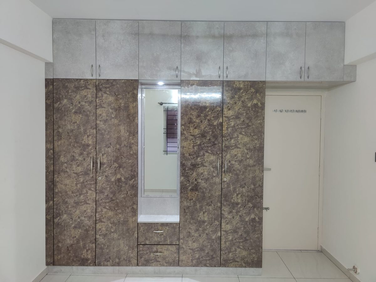Floor-to-ceiling wardrobe with stone-pattern doors, a mirror panel and loft cabinets