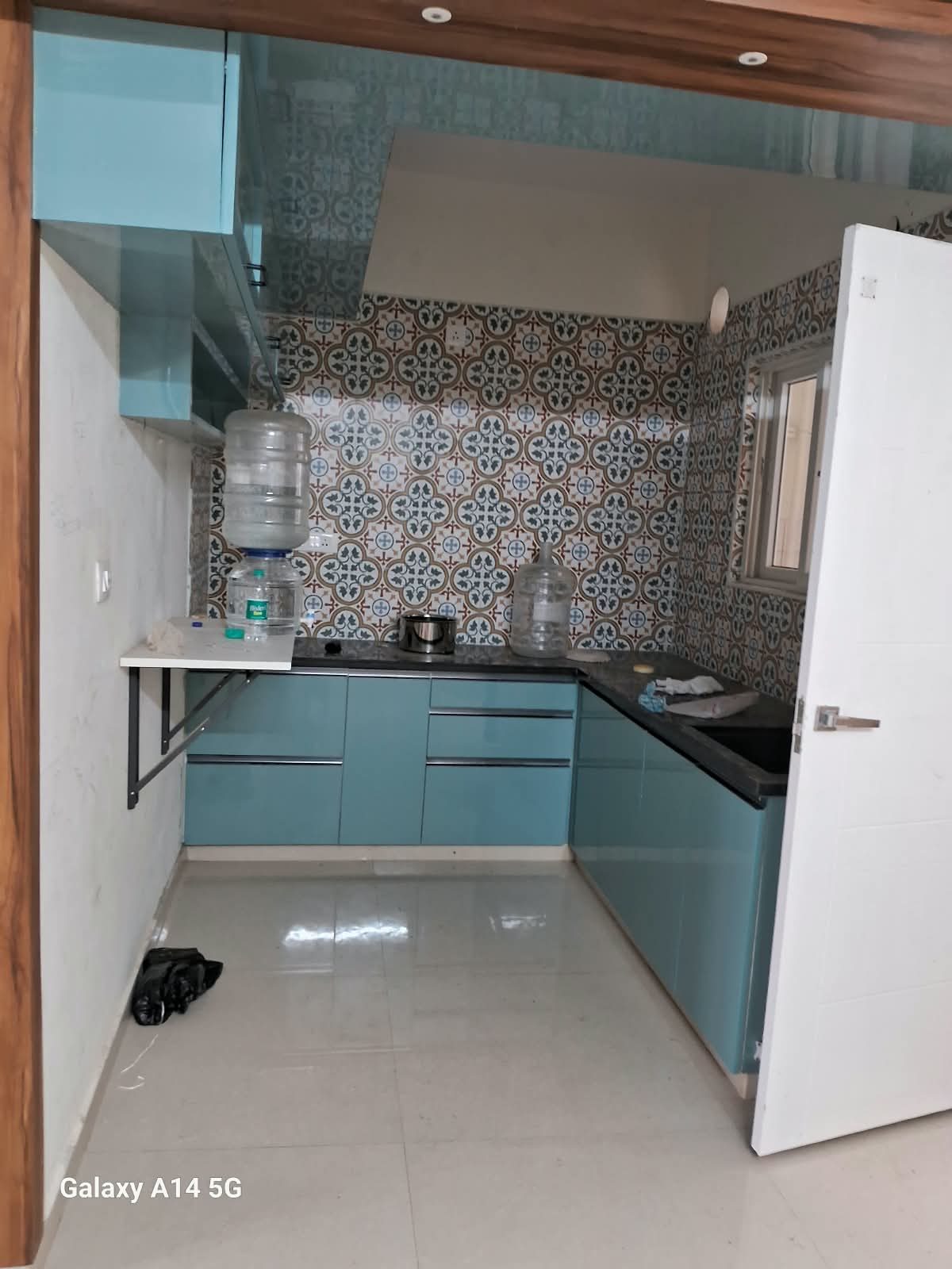 L-shaped kitchen with light-blue base cabinets, patterned wall tiles and wall storage
