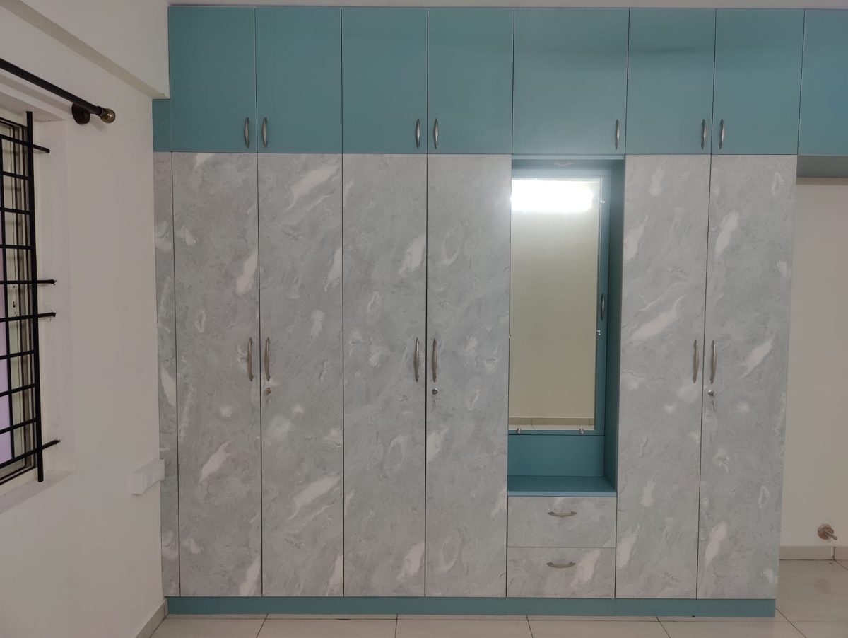 Fitted wardrobe with marble-pattern doors, a central dressing mirror and teal loft storage