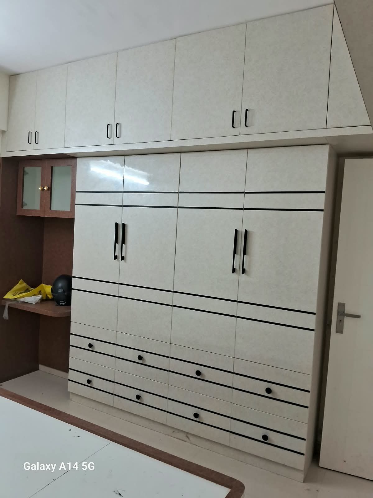 White fitted wardrobe with drawers, a study niche and overhead lofts